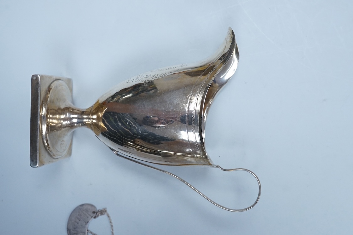 A George III silver cream jug, of oval form, London, 1801, 11cm, a George III silver helmet shaped cream jug, London, 1793, a George III small silver sugar pail, London, 1799 and a George V silver 'whisky' label, 8.4oz.